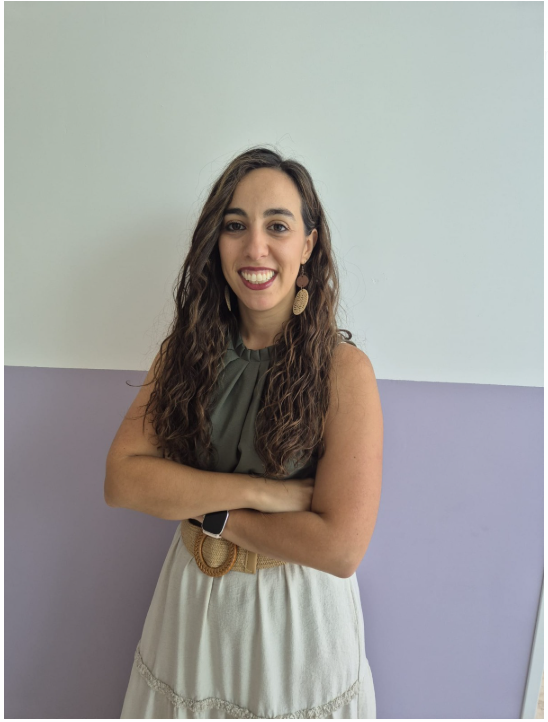 Una mujer que lleva una chaqueta verde y una camisa blanca sonríe a la cámara.
