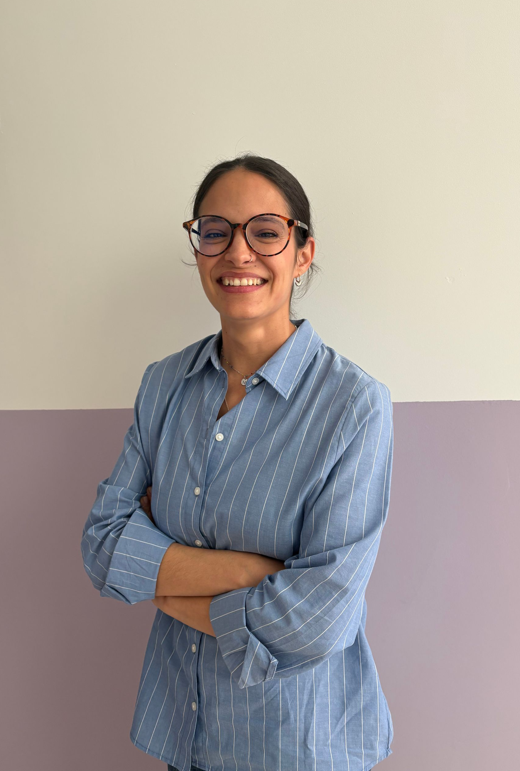 Una mujer que lleva una camiseta negra y una chaqueta gris sonríe a la cámara.