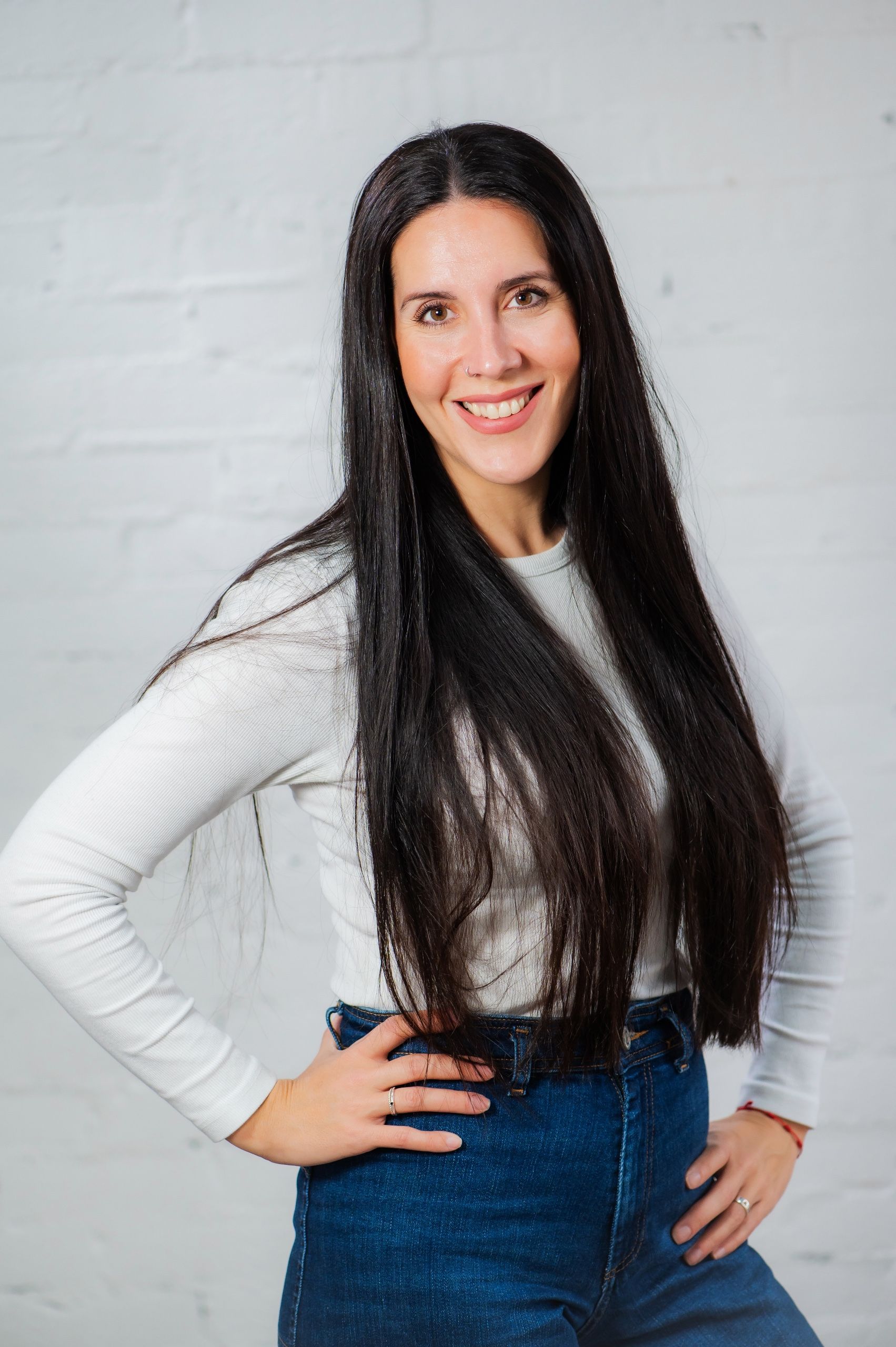 Una mujer que lleva una camiseta negra y una chaqueta gris sonríe a la cámara.