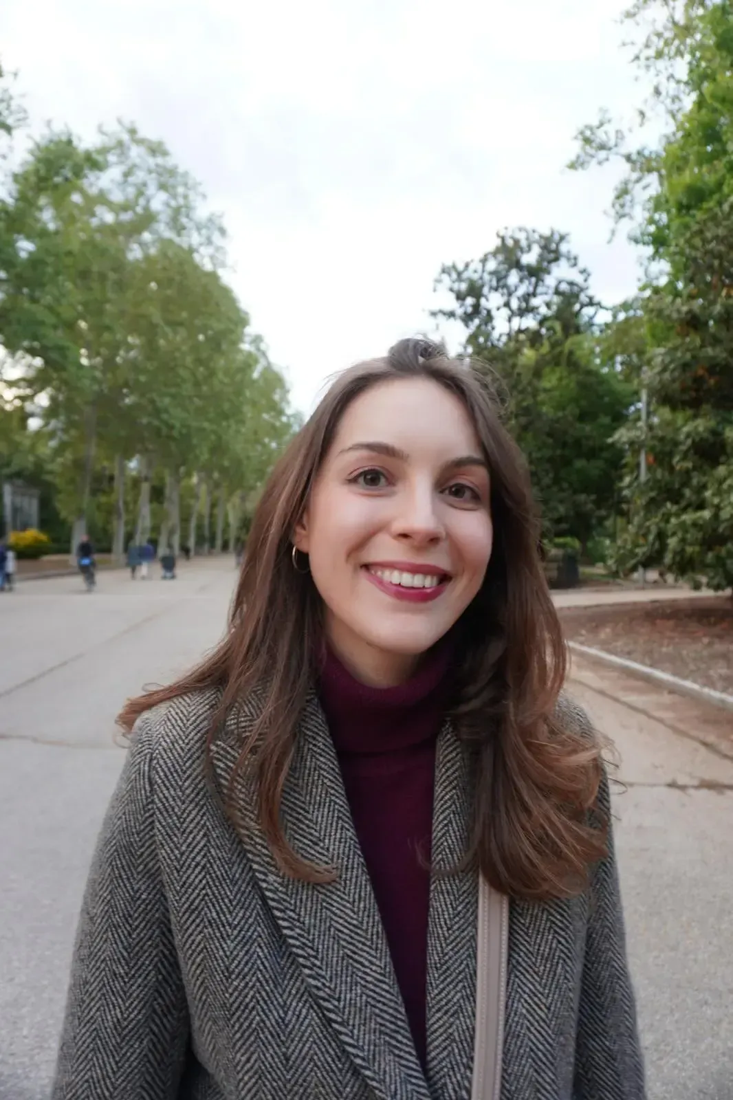 Una mujer que lleva una camiseta negra y una chaqueta gris sonríe a la cámara.