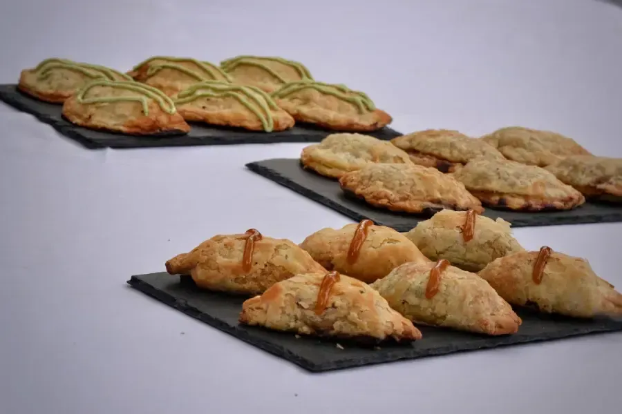 Variedad de pasteles y galletas dispuestos en platos de pizarra negra sobre una superficie blanca.
