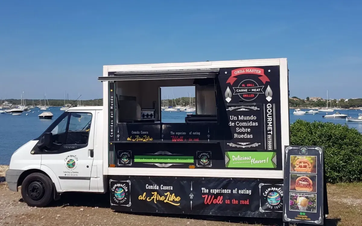 Camión de comida blanco con ventana de servicio abierta y paneles de menú negros estacionado