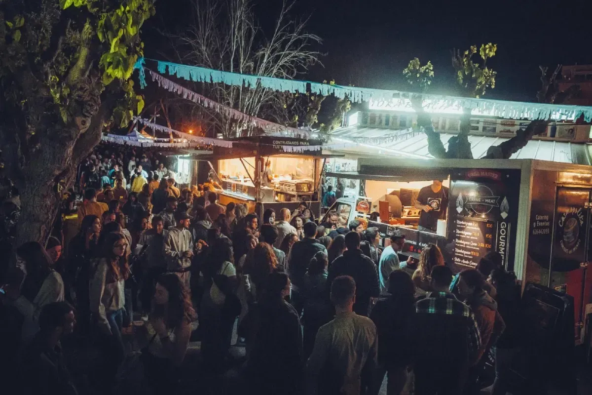 Mercado nocturno al aire libre abarrotado de gente reunida alrededor de puestos de comida brillantemente iluminados