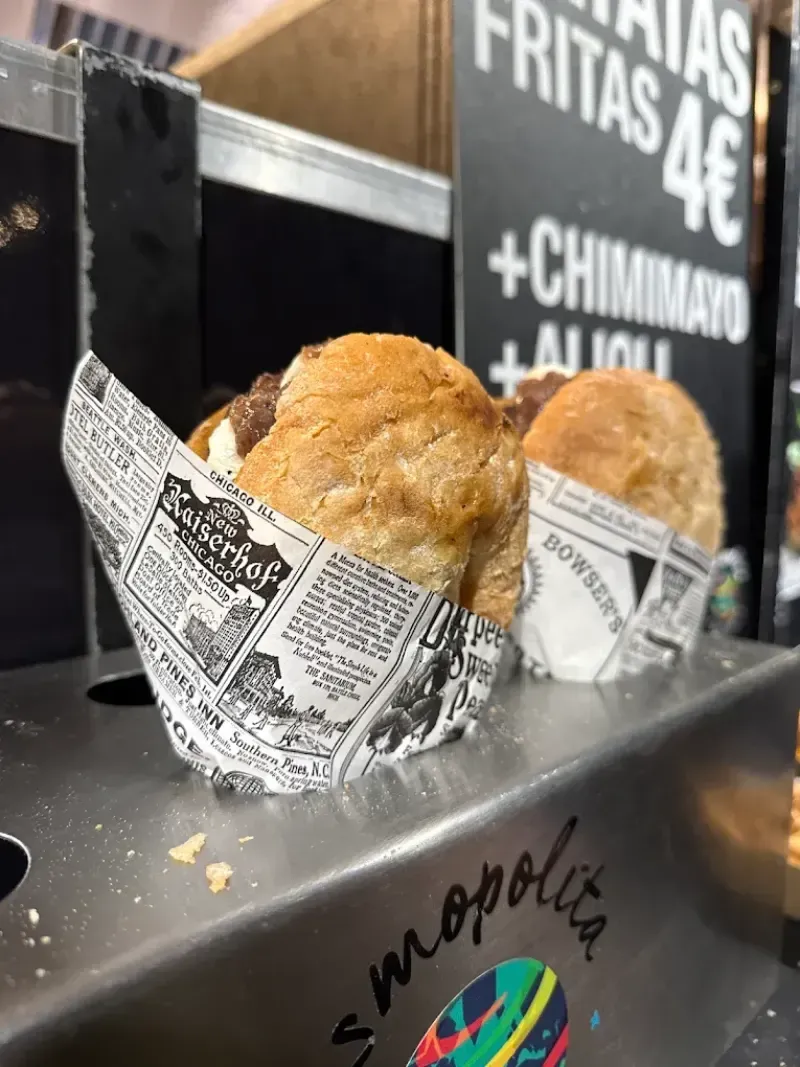 Dos sándwiches horneados envueltos en papel sobre un mostrador de metal en un puesto de comida.