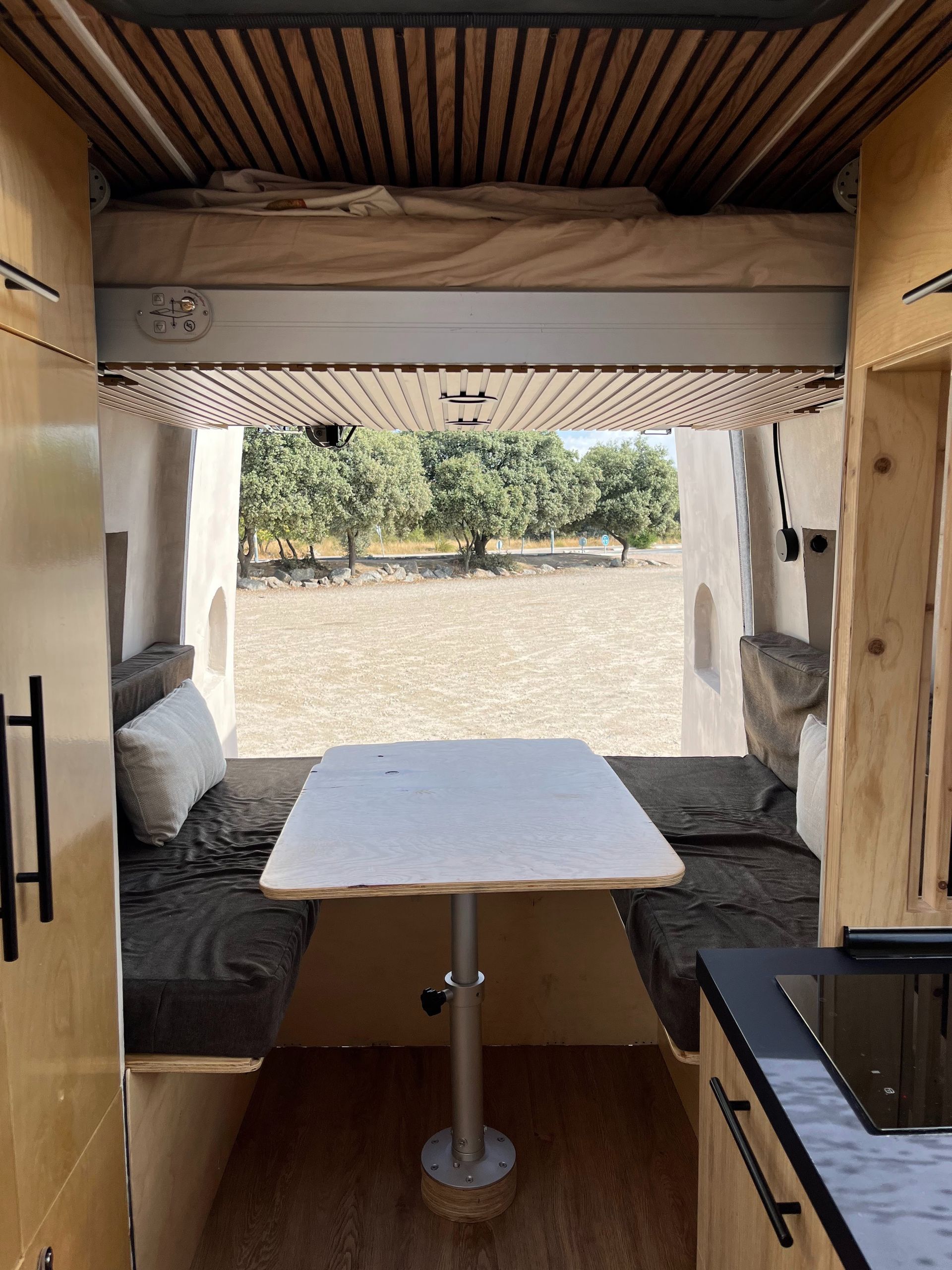 El interior de una autocaravana con una mesa y una cama.