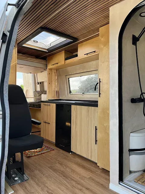 El interior de una furgoneta con armarios de madera y un baño.
