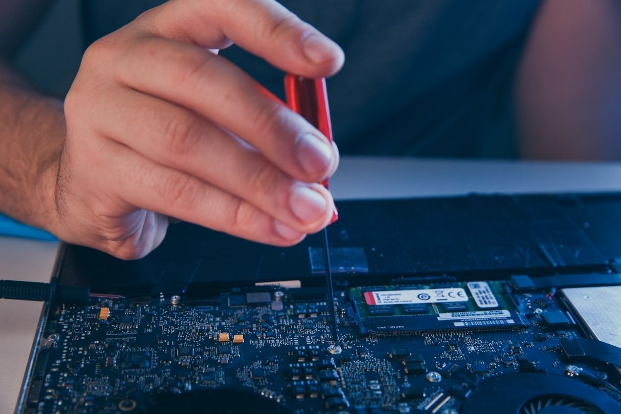 Una persona está arreglando una computadora portátil con un destornillador.
