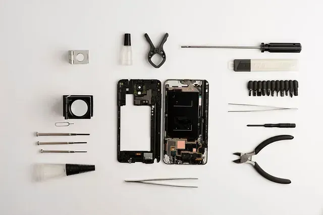 Se está reparando un teléfono celular con herramientas sobre una mesa.