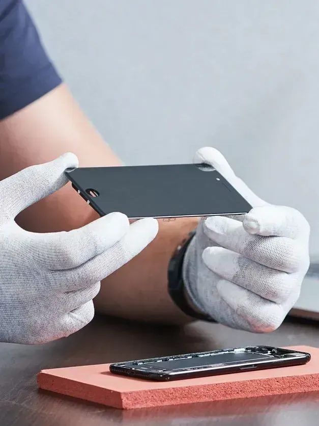 Una persona que lleva guantes blancos sostiene un teléfono celular en sus manos.