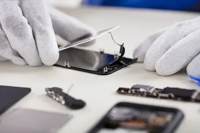 Una persona está reparando un teléfono celular en una mesa.