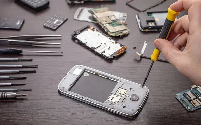 Una persona está arreglando un teléfono celular con un destornillador.