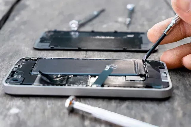Una persona está arreglando un teléfono celular con un destornillador.