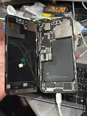 Una persona sostiene un iPhone X roto en su mano.
