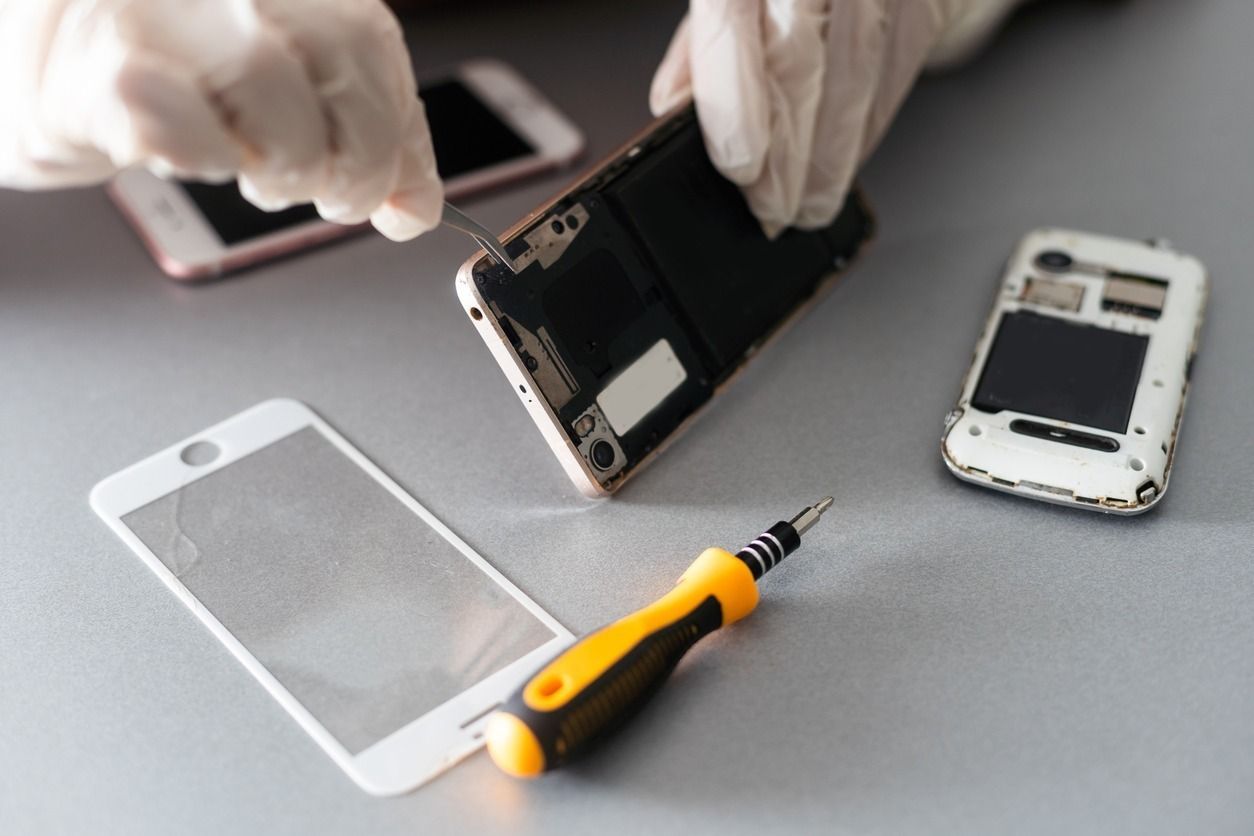 Una persona está reparando un teléfono celular con un destornillador.