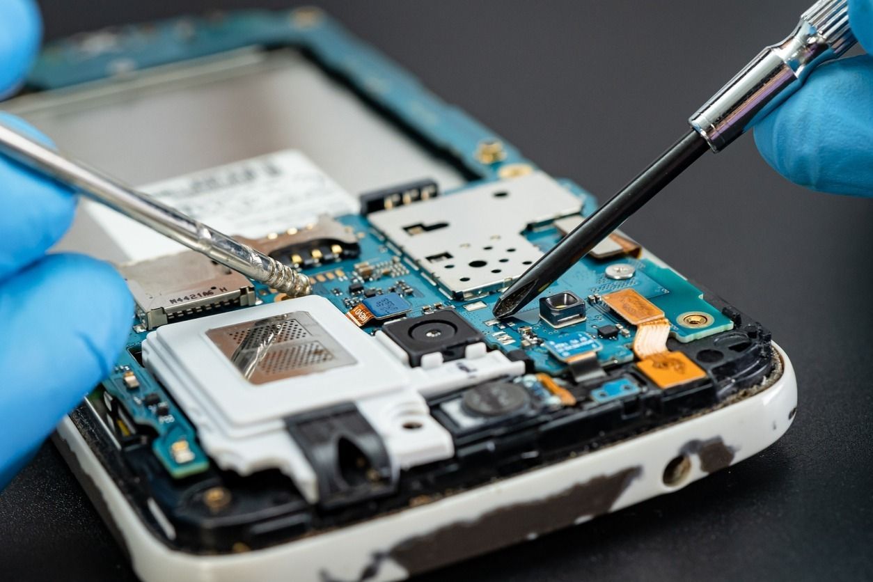 Una persona está arreglando un teléfono celular con un destornillador.