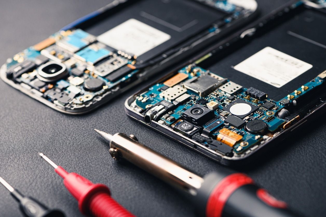 Se están reparando dos teléfonos celulares con herramientas sobre una mesa.