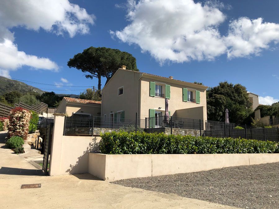 Maison en crépi beige avec des volets verts