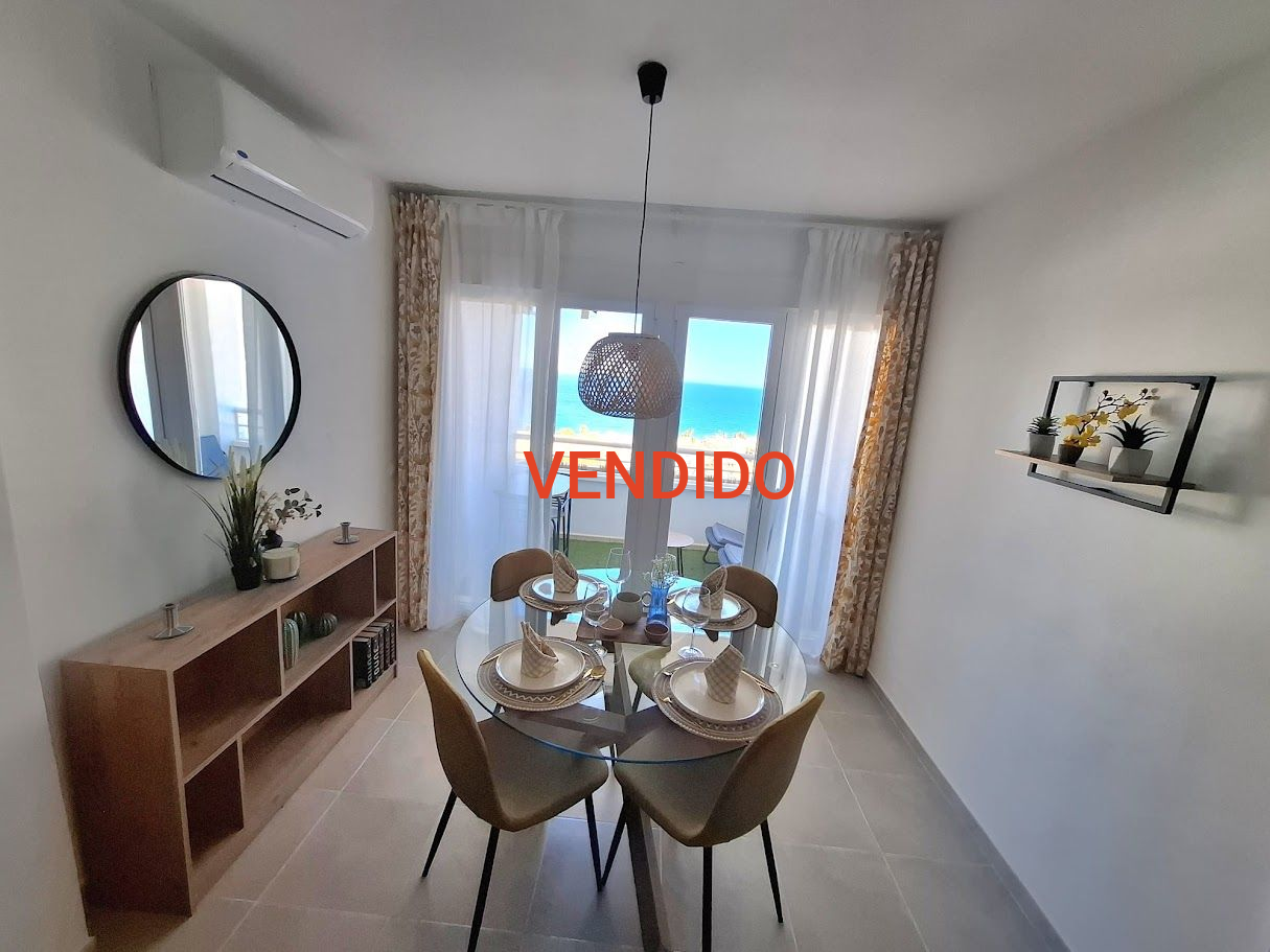 Comedor con mesa redonda para dos con vista al mar a través de una puerta corrediza.