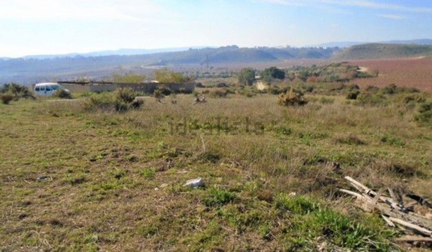 Un gran campo de hierba con una casa al fondo