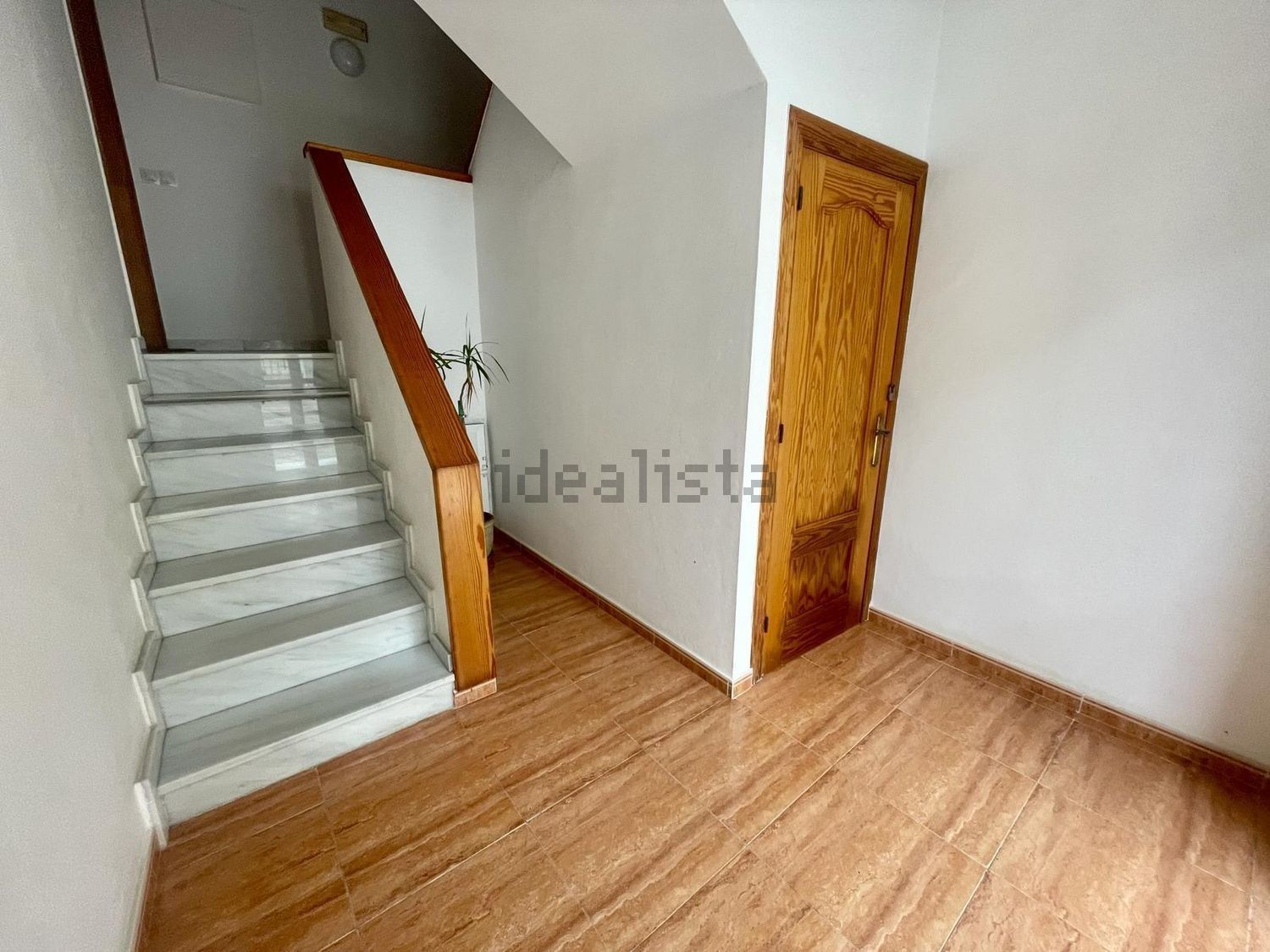 Un pasillo con escaleras que conducen al segundo piso y una puerta.