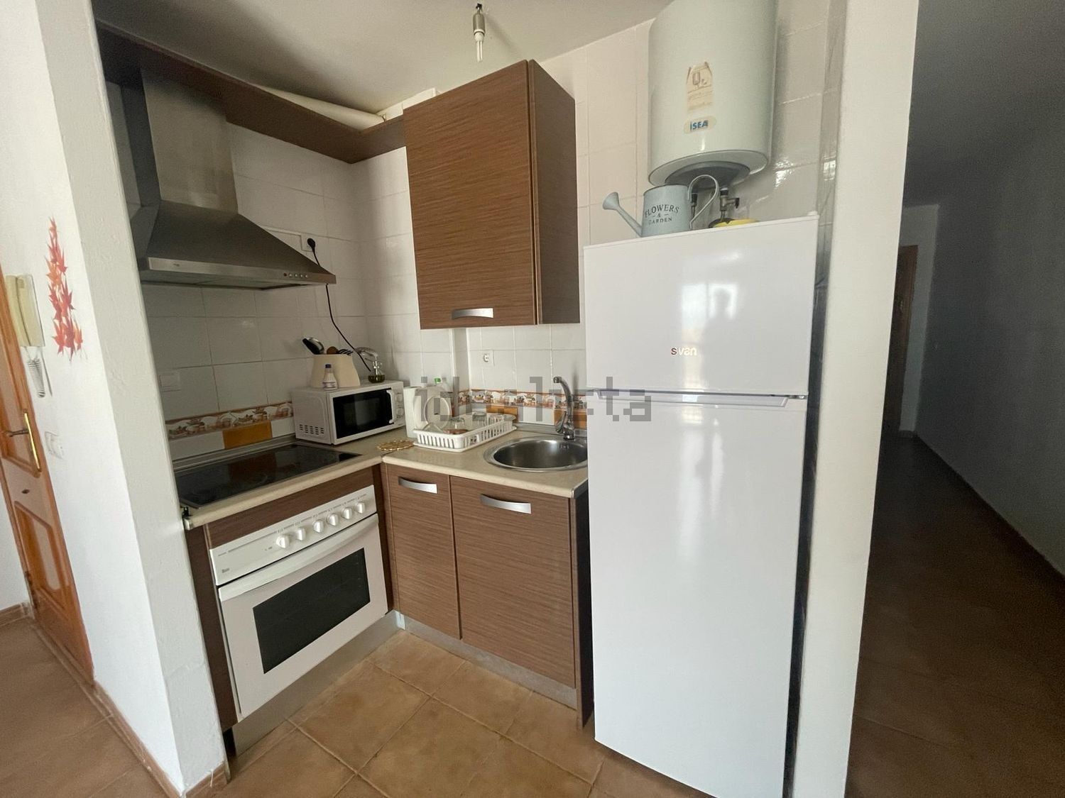 Una cocina con refrigerador, estufa, fregadero y calentador de agua.