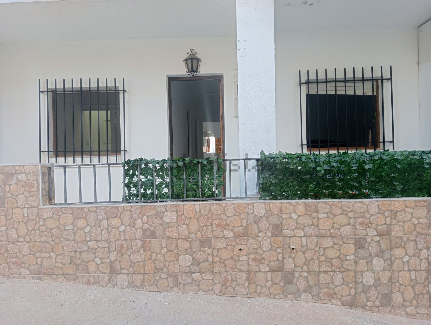 Una casa blanca con un muro de piedra detrás