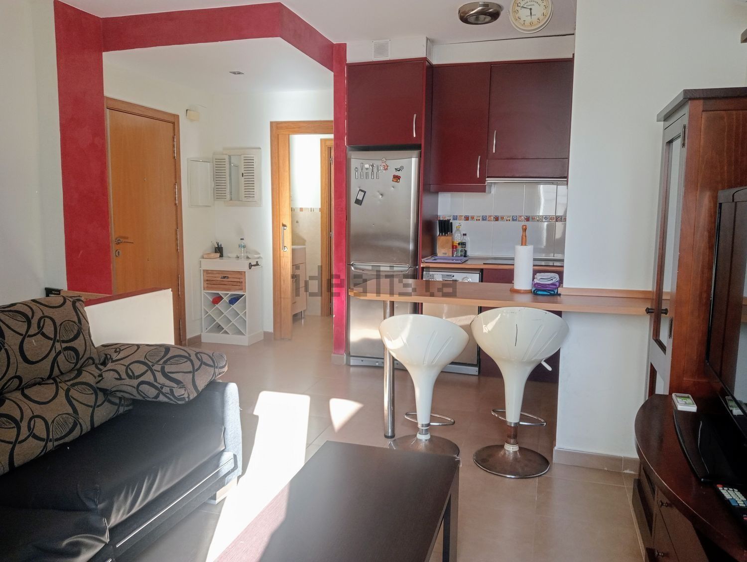 Una sala de estar con un sofá y dos taburetes de bar.