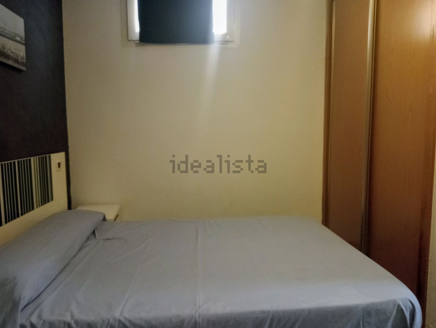 Un dormitorio con una cama y una ventana con la palabra idealista en la pared.