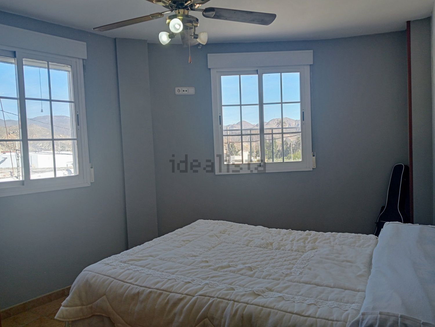 Un dormitorio con una cama y un ventilador de techo.