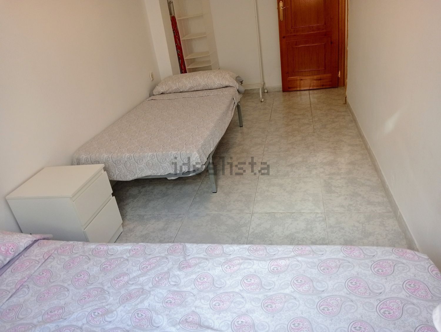 Un dormitorio con dos camas, una mesita de noche y una puerta.