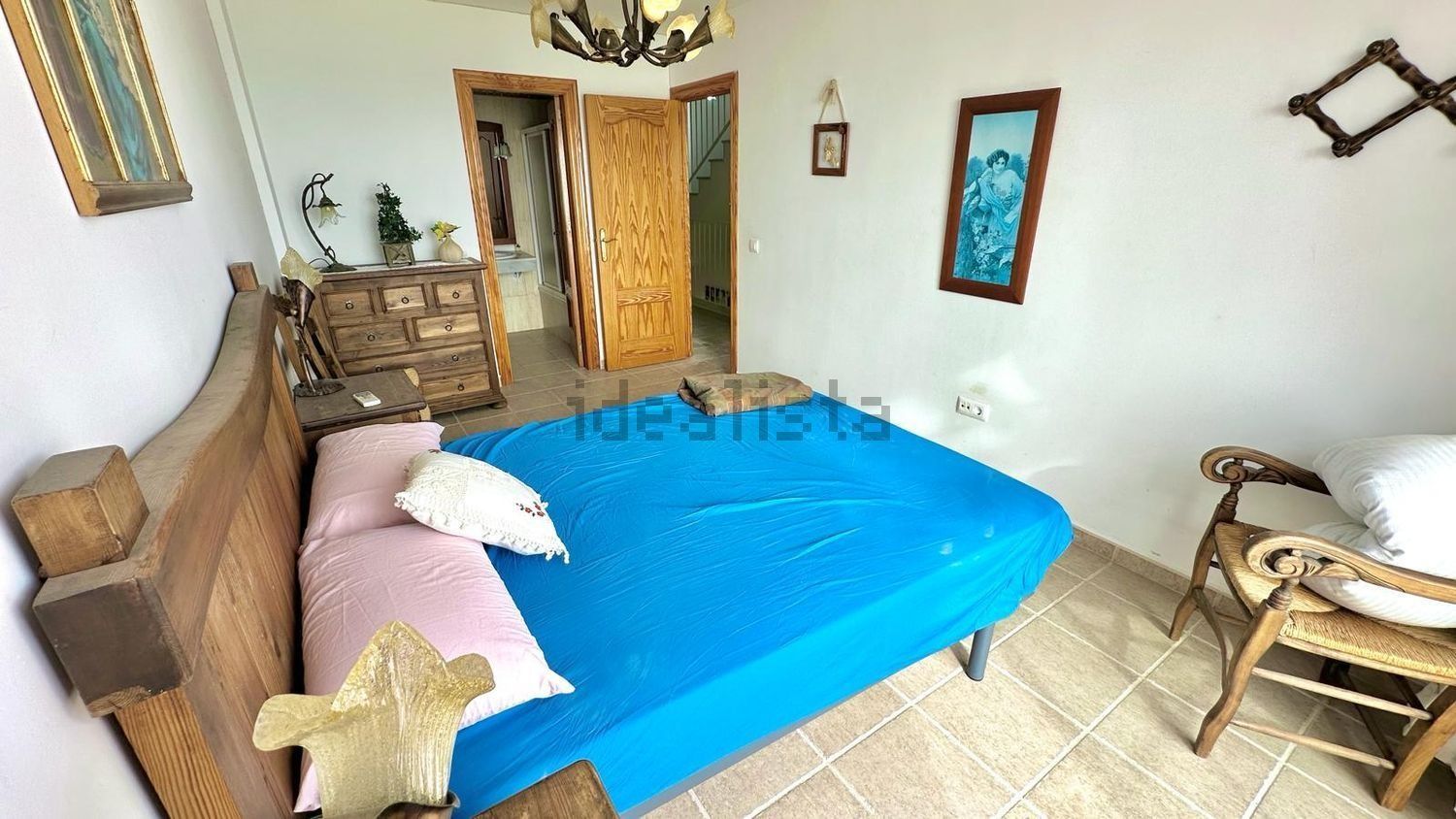 Un dormitorio con una cama azul y una silla.