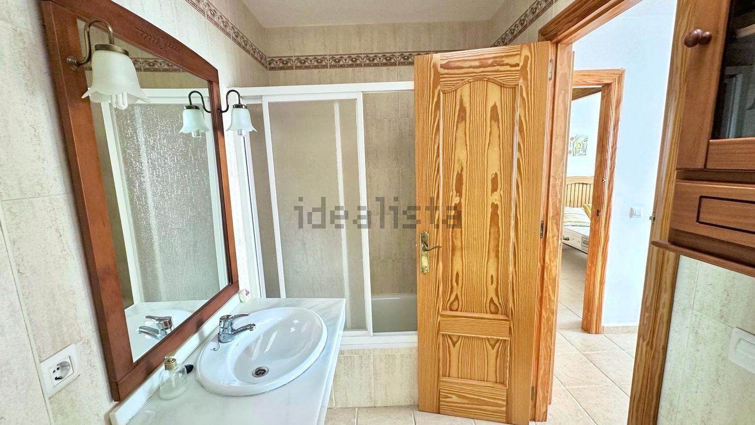 Un baño con lavabo, espejo y cabina de ducha.