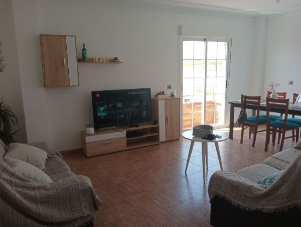 Una sala de estar con sofá, mesa y televisión.