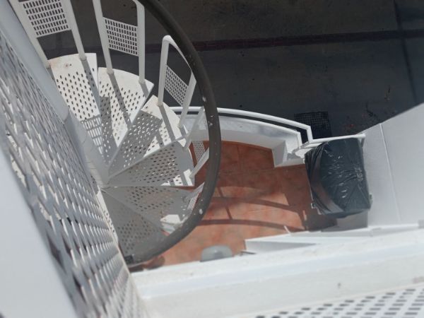 Una escalera de caracol blanca con barandilla negra.