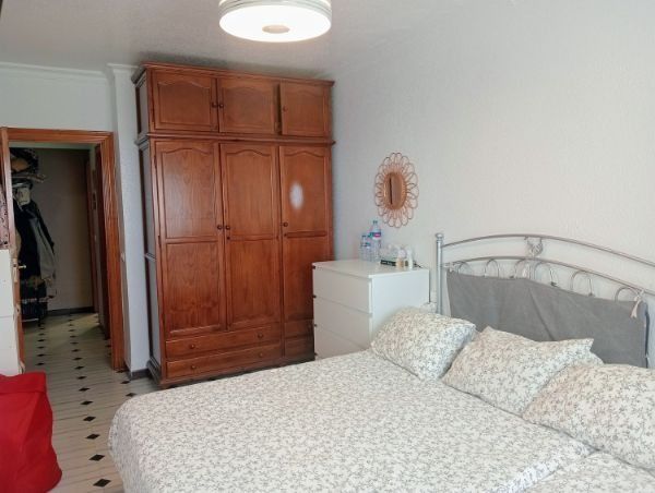 Un dormitorio con cama, armario, cómoda y espejo.