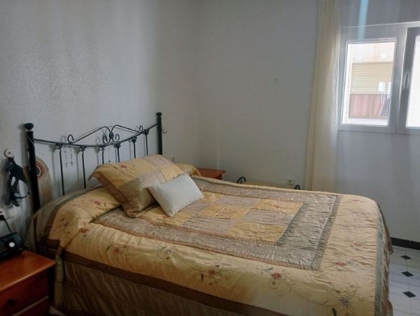 Un dormitorio con una cama, mesita de noche y ventana.