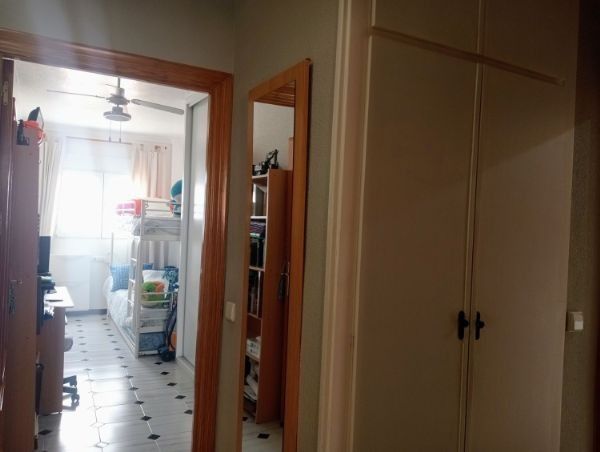 Un pasillo que conduce a un dormitorio con una litera y un ventilador de techo.
