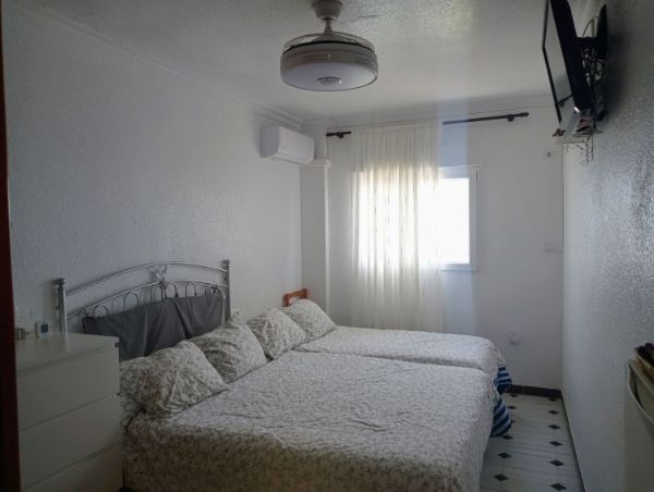 Un dormitorio con dos camas, un ventilador de techo y un televisor.