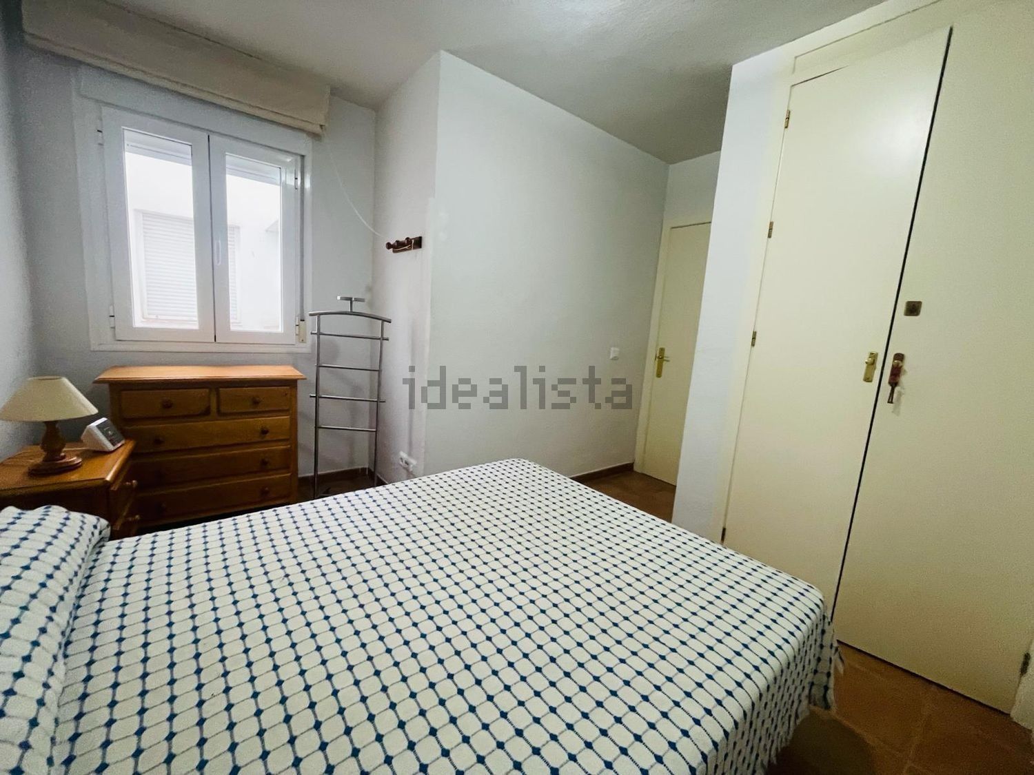 Un dormitorio con cama, cómoda, mesita de noche y lámpara.