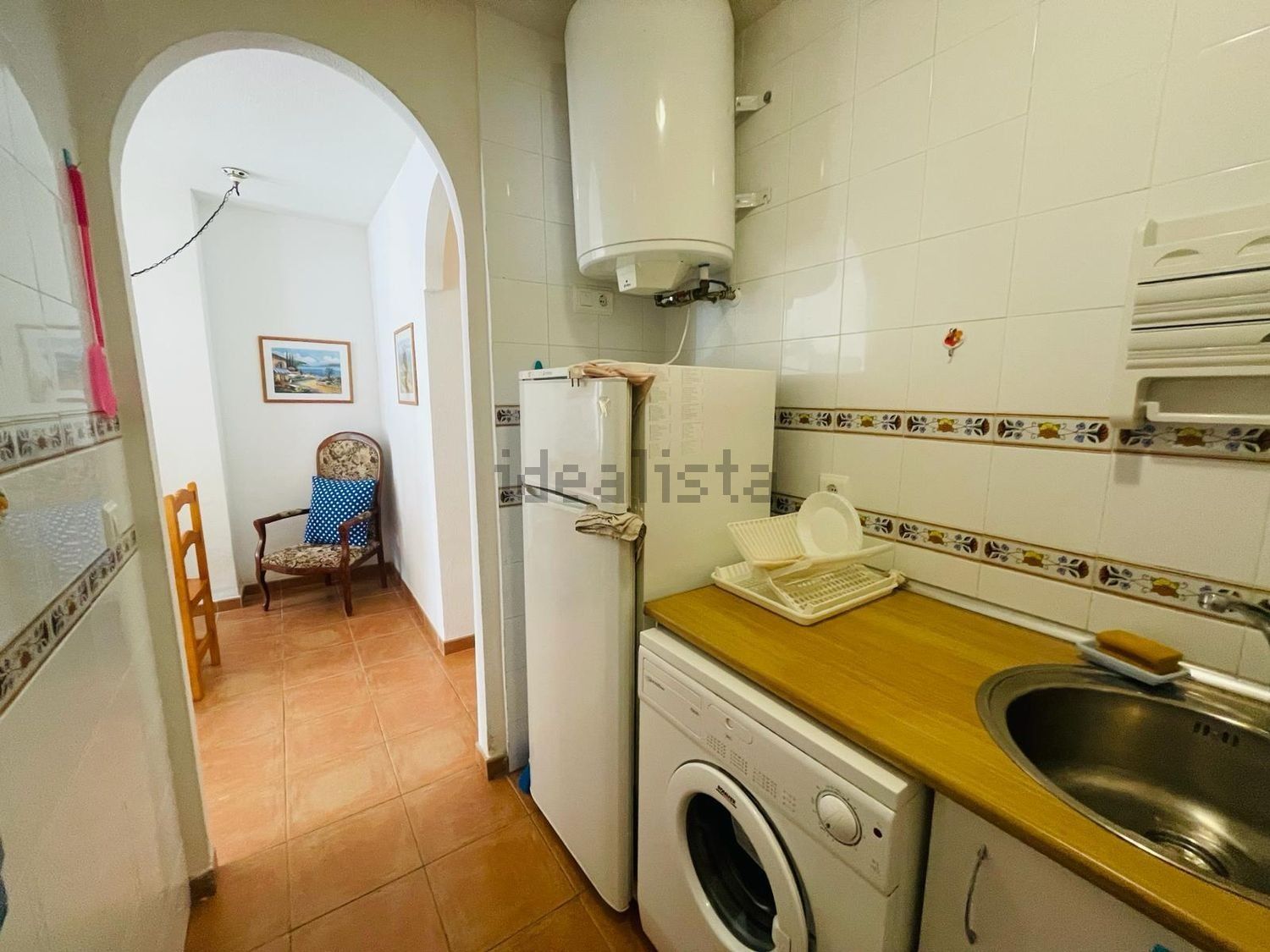 Una cocina con frigorífico, lavadora y fregadero.