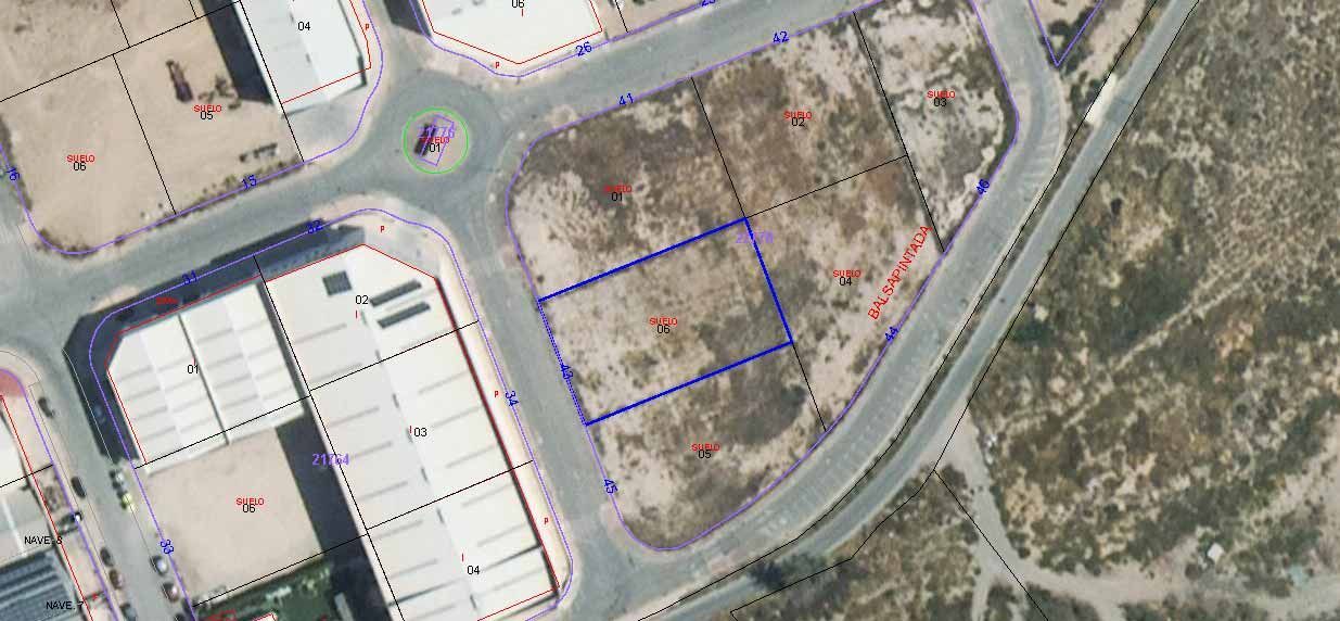 Vista aérea de parcelas industriales con rotonda y terreno abierto, las parcelas están delineadas en azul.