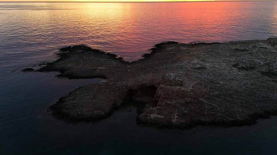 Una pequeña isla en medio del océano al atardecer.
