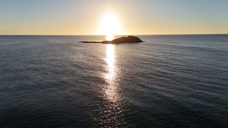 Una pequeña isla en medio del océano al atardecer.