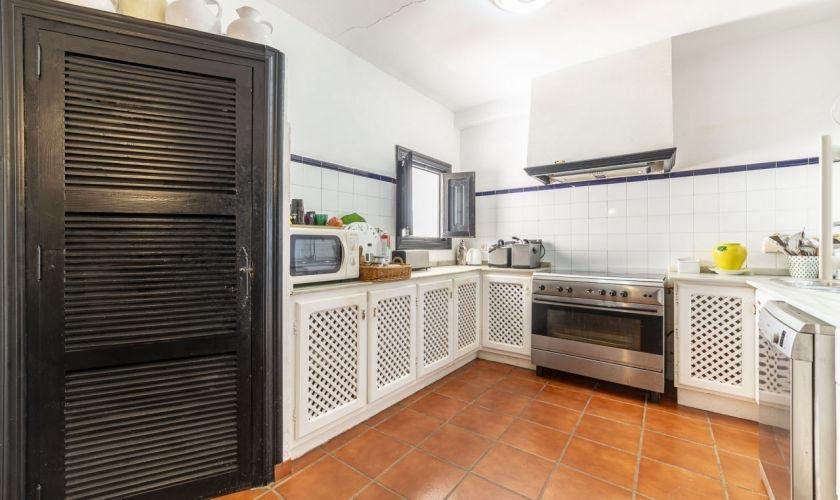 Una cocina con gabinetes blancos, una estufa, un microondas y un refrigerador.