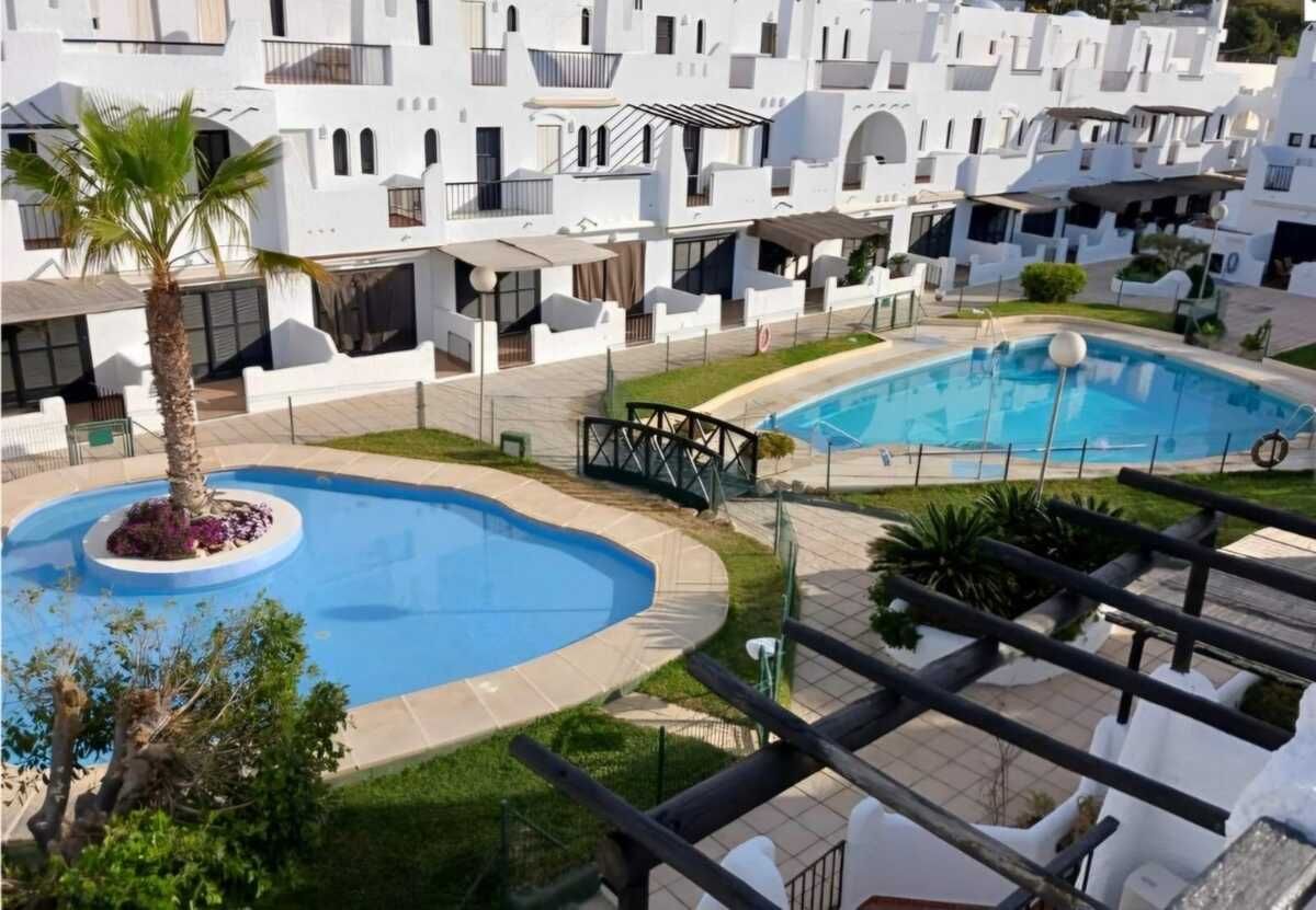 Comedor con mesa y sillas, que conduce a una cocina con gabinetes blancos.