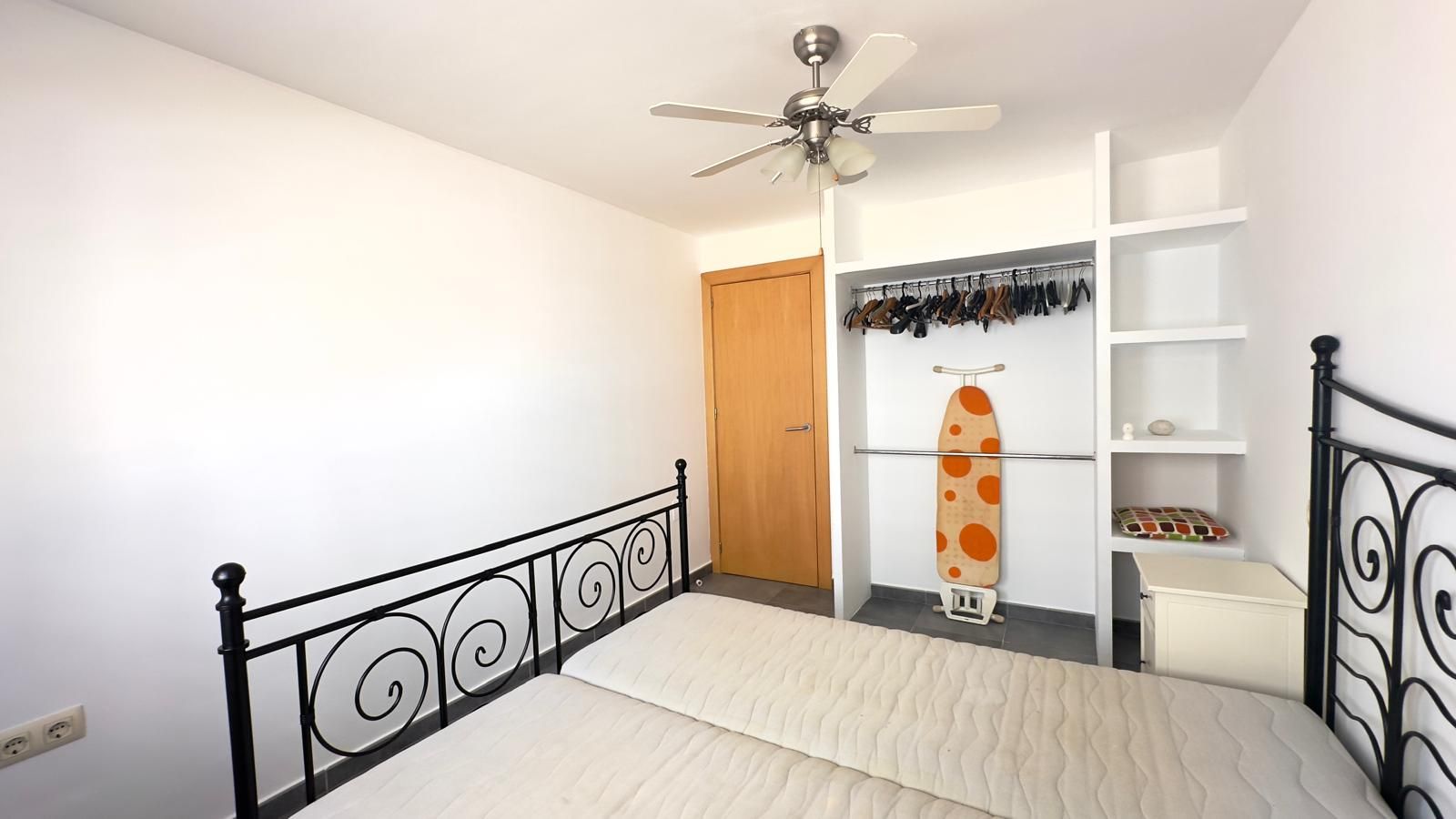 Balcón con vista al paisaje urbano y al océano, con barandilla azul, edificios blancos y cielo despejado.