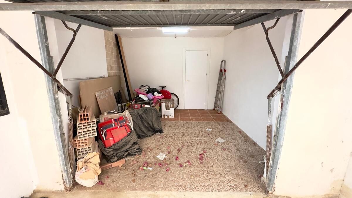 Pequeño espacio al aire libre con un sillón, una mesa pequeña y dos pequeñas ventanas bajo un techo parcial.