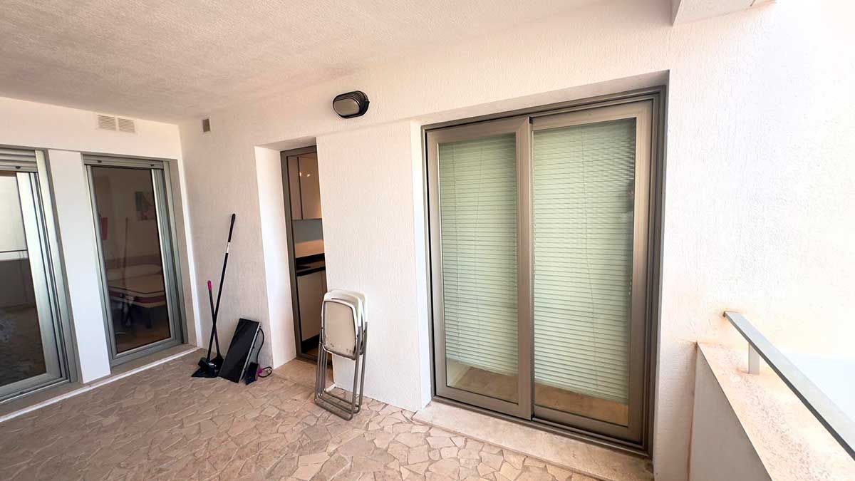 Baño con paredes efecto piedra, lavabo flotante, inodoro y estantería de madera con toallas.