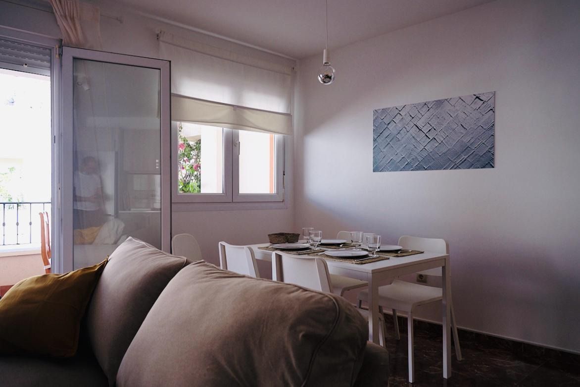 Una mesa y sillas en un balcón con flores al fondo.