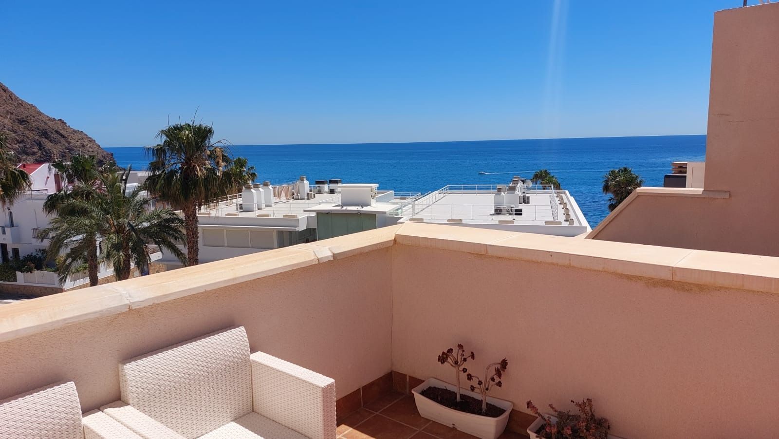 Un balcón con vista al mar y palmeras.